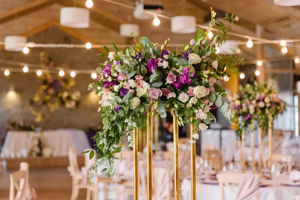 O alto suporte na cor de ouro decorado com flores em uma mesa de férias . — Fotografia de Stock