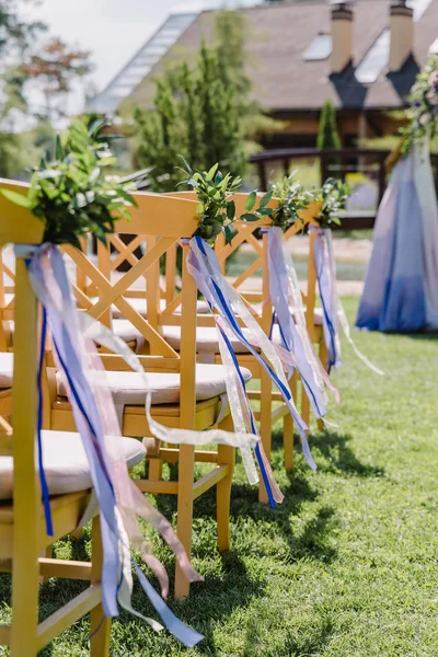 Cadeiras de madeira em um casamento. As cadeiras decoradas com botões e fitas para os hóspedes — Fotografia de Stock