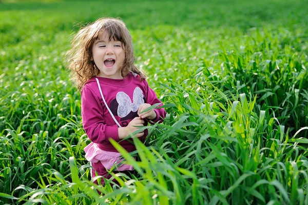 小女孩在夕阳的时候在绿地, 面带微笑 — 图库照片