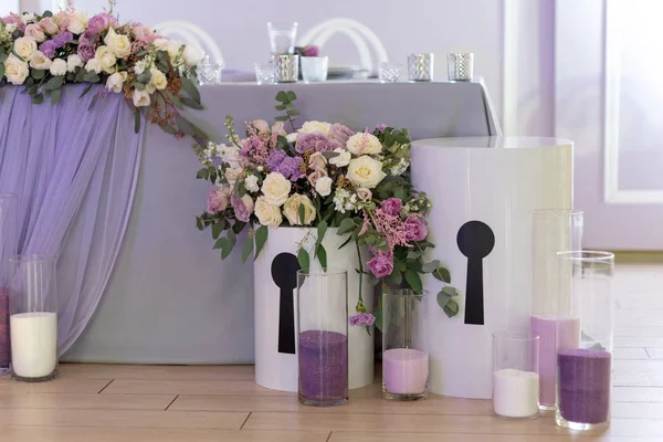 Big boxes with flowers. Candles in glass flasks on a parquet