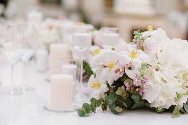 Açık tonlarında beyaz mumlar ve çiçekler ile düğün masasılüks dekorasyon