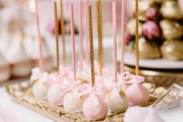 Malé a lahodné dortíky v růžové na zlatém stojanu s půvabnou výzdobou — Stock fotografie