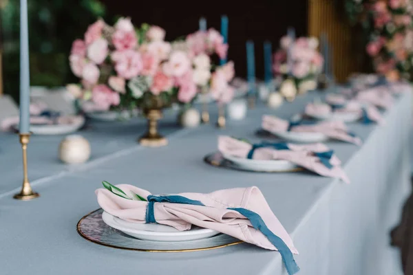 Stilvolles und schönes Hochzeitstisch-Service mit blauer Tischdecke, festlichem Geschirr und zartrosa Servietten — Stockfoto