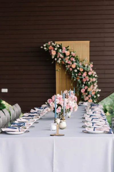 Mesa de casamento retangular longa decorada com toalha de mesa azul, velas, flores luxuosas . — Fotografia de Stock