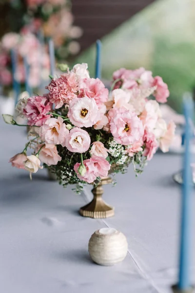 Una elegante composición de flores frescas en un jarrón antiguo y un pequeño y bonito candelero . — Foto de Stock