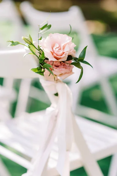 Een elegant boeket roze bloemen en groen zijdelings gebonden op de rug van een witte stoel — Stockfoto