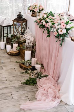 Düğün masasında güzel çiçekler ve büyük cam mataralarda mumlar yanında duruyor..