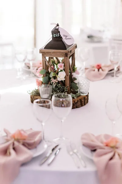 Lâmpada de madeira bonita cheia de verdes e flores adorna uma mesa inchada — Fotografia de Stock