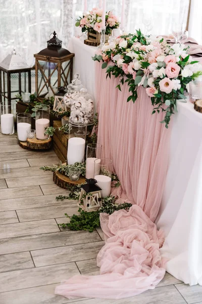 Lindas flores na mesa de casamento e velas em grandes frascos de vidro em stands de madeira perto dele . — Fotografia de Stock
