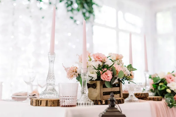 Rosa Kerzen in hohen Glasleuchtern und Blumen in einem kleinen Holzkästchen — Stockfoto