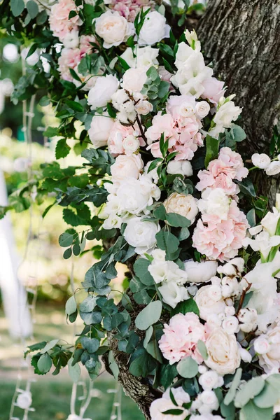 Beautiful and gentle flowers decorate the trunk of a living tree in the garden for a solemn wedding ceremony