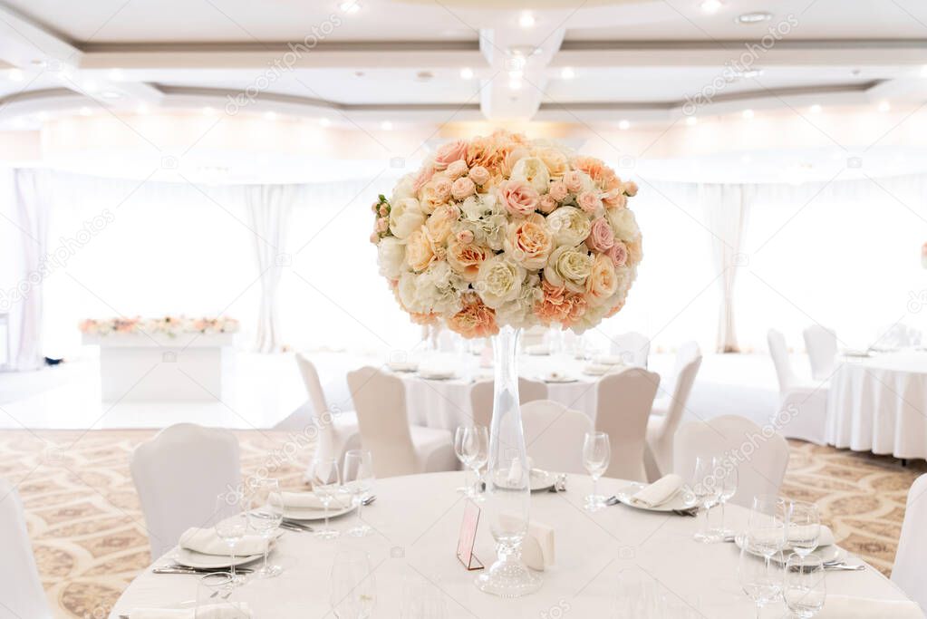 A large wedding bouquet of an assortment of fresh roses of pastel shades adorns the festive table