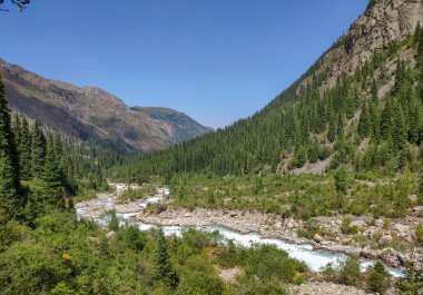Almat şehri yakınlarındaki Kazakistan'da Tien Shan sisteminin Trans-Ili Alatau sıradağları. Yaz ortasında bulutların altında karla kaplı kayalık zirveler