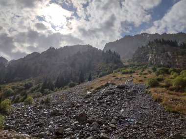 Almat şehri yakınlarındaki Kazakistan'da Tien Shan sisteminin Trans-Ili Alatau sıradağları. Yaz ortasında bulutların altında karla kaplı kayalık zirveler