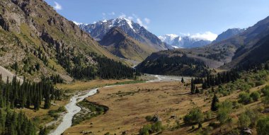 Almat şehri yakınlarındaki Kazakistan'da Tien Shan sisteminin Trans-Ili Alatau sıradağları. Yaz ortasında bulutların altında karla kaplı kayalık zirveler