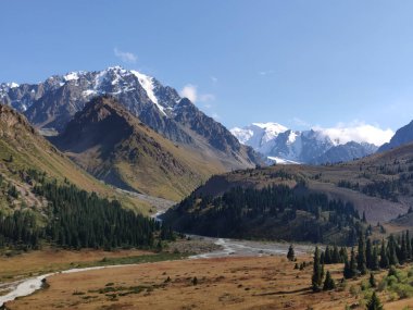 Almat şehri yakınlarındaki Kazakistan'da Tien Shan sisteminin Trans-Ili Alatau sıradağları. Yaz ortasında bulutların altında karla kaplı kayalık zirveler
