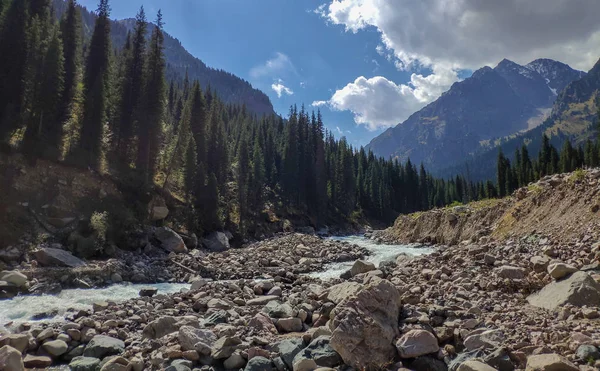 Almat şehri yakınlarındaki Kazakistan'da Tien Shan sisteminin Trans-Ili Alatau sıradağları. Yaz ortasında bulutların altında karla kaplı kayalık zirveler