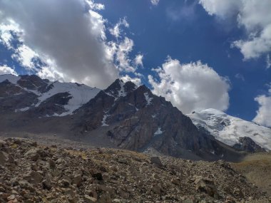 Almat şehri yakınlarındaki Kazakistan'da Tien Shan sisteminin Trans-Ili Alatau sıradağları. Yaz ortasında bulutların altında karla kaplı kayalık zirveler