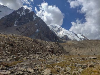 Almat şehri yakınlarındaki Kazakistan'da Tien Shan sisteminin Trans-Ili Alatau sıradağları. Yaz ortasında bulutların altında karla kaplı kayalık zirveler