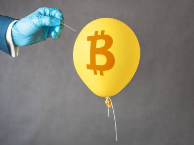 Sarı balonda Bitcoin kripto para sembolü. Erkek iğneyi hava balonuna doğru tutar. Mali risk kavramı.