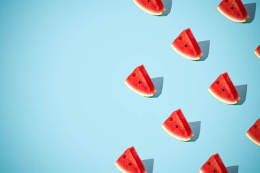 Minimal flat lay food texture. Summer abstract trendy fresh concept. Red Watermelon slice pattern on bright light blue background, copy space. .