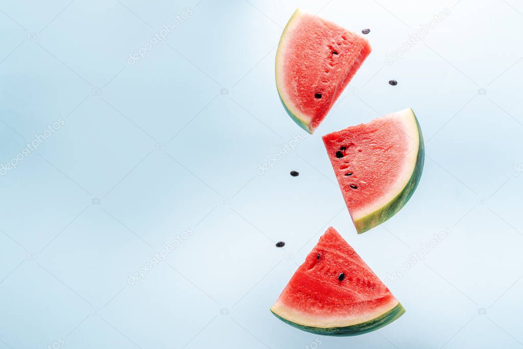 Watermelon slice falling on pastel background. Floating fruits in the air. Flying red fruits. Summer background. Trend colors, copy space.