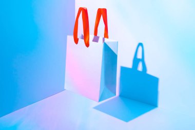 Neon ışıkta uçan kağıt poşet. Tüketim kavramı, alışveriş kolaylığı. Boşluk eğilimi pastel renkleri kopyala.