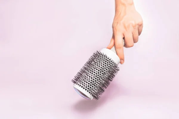 Had holding hair brush tool under trendy color background with copy space and soft light. Stylish Professional Barber hair cut tools, Hairdresser salon concept, Haircut accessories.