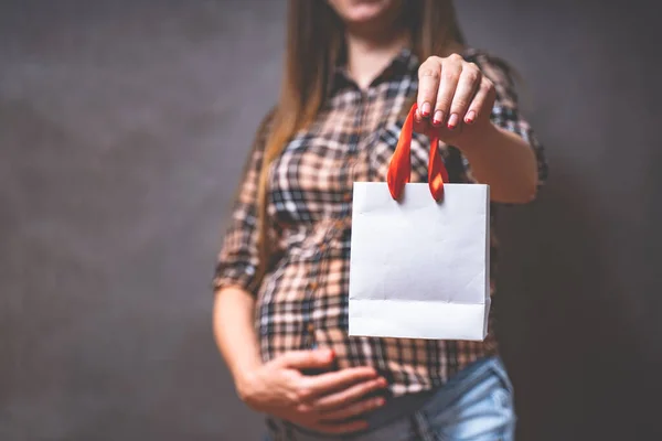 Hamilelik alışverişi, annelik, insanlar ve beklenti konsepti. Elinde alışveriş çantası olan hamile bir kadın koca karnına dokunuyor. Tonu ayarlanmış resim — Stok fotoğraf