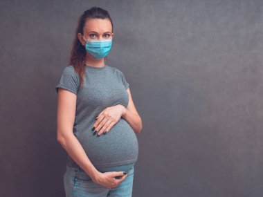 Pregnancy And Infection concept. Pregnant Woman in Medical Face Mask against flu and viruses. Healthcare concept, copy space.