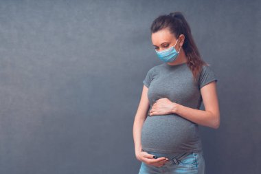 Pregnancy And Infection concept. Pregnant Woman in Medical Face Mask against flu and viruses. Healthcare concept, copy space.