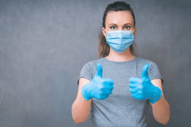 Yang woman show ok sign. Healthcare and Infection concept. Woman in Medical Face Mask and blue gloves against flu and viruses, copy space.