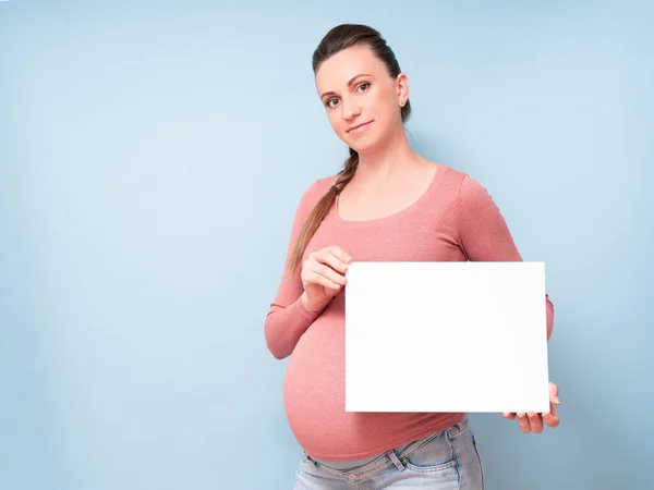 Mladá Krásná Těhotná Žena Izolovaném Modrém Pozadí Drží Prázdný List — Stock fotografie