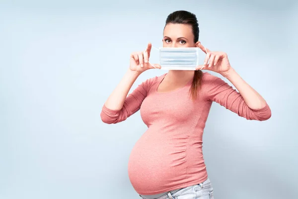 Grip ve virüslere karşı maskeli hamile kadın. Sağlık sigortası konsepti, kopyalama alanı. Hamilelik ve enfeksiyon konsepti. Yüksek çözünürlük.