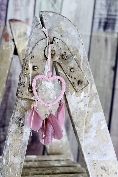 木製の塗装に掛かっている羽をかわいいピンクのハート型のドリーム キャッチャー飛び散ったビンテージはしご ぼろぼろのシックなイメージ 珍しいロマンチックな結婚式の装飾 — ストック写真