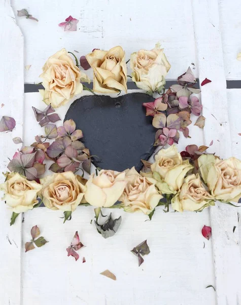 ハートの乾燥したバラとアジサイの花びらを空の黒板で白い木製の背景にビンテージ スタイルみすぼらしいシックな花画像 — ストック写真