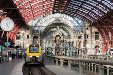 2018-10-01 Antwerp, Belçika: anıtsal tren hall, Anvers Merkez İstasyonu platformu, saat ve tren kalkış için hazır. Tüm büyük demir ve cam tonozlu tavan tarafından kapalı. Antwerp, Belçika.