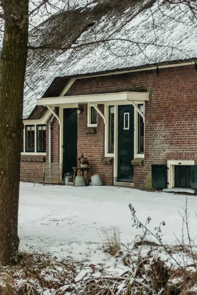 Breukelen, the Netherlands- 2010-01-14 : Compound and entrance doors of a typical farmhouse called \'de Morgenstond\' . Brick building with thatched roof and white framed, green painted doors and windows. small pent roof above doors. Decoration of old