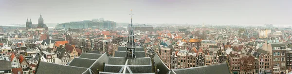 Kilise çatısı ve küçük kule üzerindeki Oude Kerk (Eski Kilise) kulesi ve Amsterdam 'ın eski ortaçağ evleri ile şehir içi manzarası. Arka planda ise Saint N Bazilikası (Basiliek van de Heilige Nicolaas) yer almaktadır.