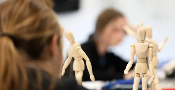 Visual Art high school students working from wooden mannequins practicing drawing human fugure and correct proportion. Artists being creative the art room. Creativity inspiration concept