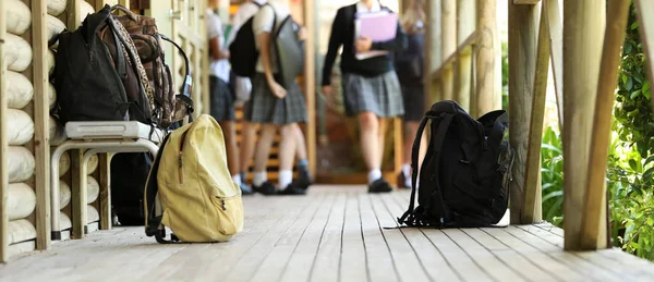 students legs walking between classes during lesson break. school bags back packs and duffle bags with school kids in uniform in the background. Education concept