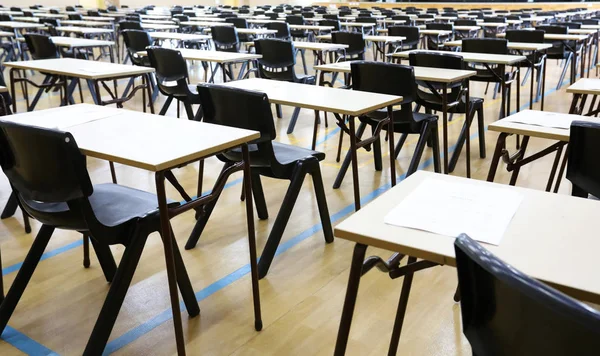 View of large exam room hall and examination desks tables lined up in rows ready for students at a high school to come and sit their exams tests papers.