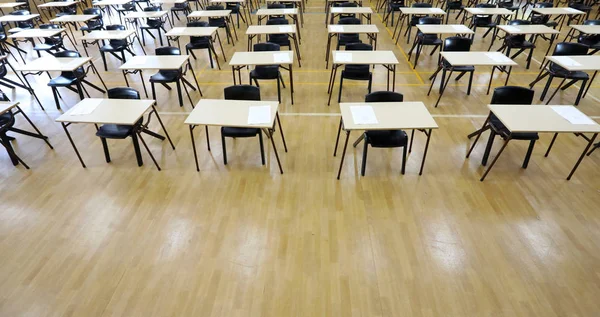 interesting view from above of large exam room hall and examination desks tables lined up in rows ready for students at a high school to come and sit their exams tests papers.