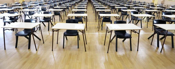 View of large exam room hall and examination desks tables lined up in rows ready for students at a high school to come and sit their exams tests papers.