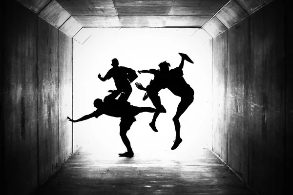 silhouetted group of male high school students exiting a tunnel jumping with joy and excitement. Creative concept for education, happiness, finishing exams and completing school, start of holidays or graduation.