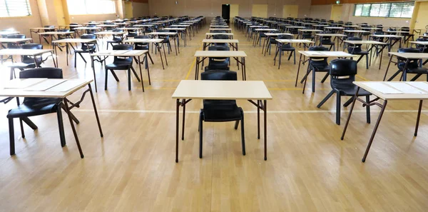 wide view of an exam examination room or hall set up ready for students to sit test. multiple desks tables and chairs. Education, school, student life concept