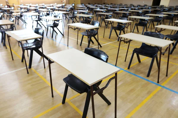 view of an exam examination room or hall set up ready for students to sit test. multiple desks tables and chairs. Education, school, student life concept