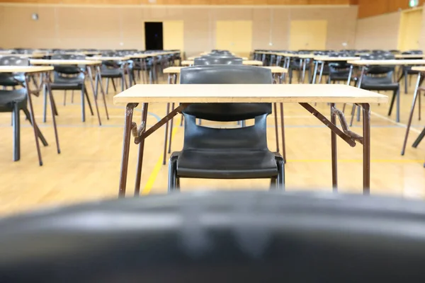 low angle view of an exam examination room or hall set up ready for students to sit test. multiple desks tables and chairs. Education, school, student life concept