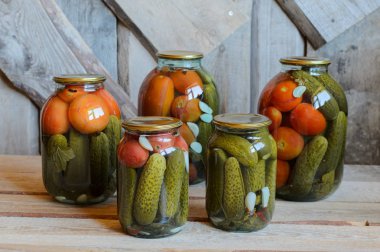 Konserve domates ve salatalık ile cam kavanozlar. Ahşap arka plan