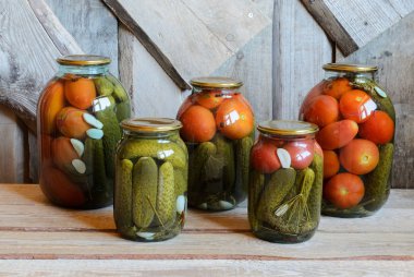 Konserve domates ve salatalık ile cam kavanozlar. Ahşap arka plan